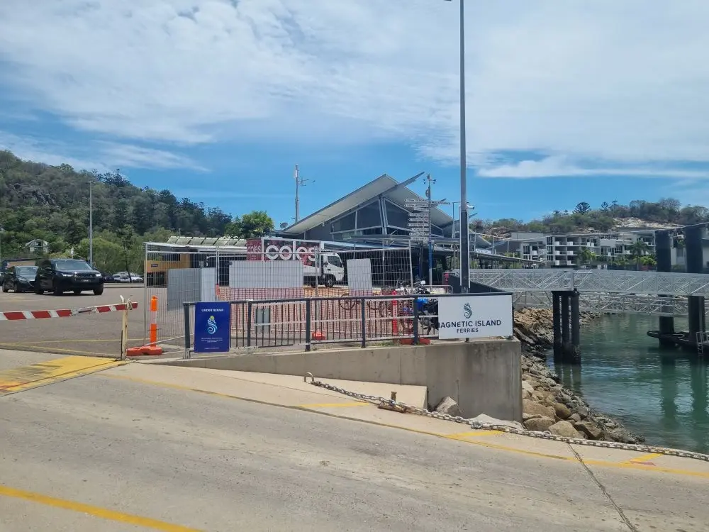 Magnetic Island ferry terminal building beside the water, with the vehicle marshalling area in the foreground