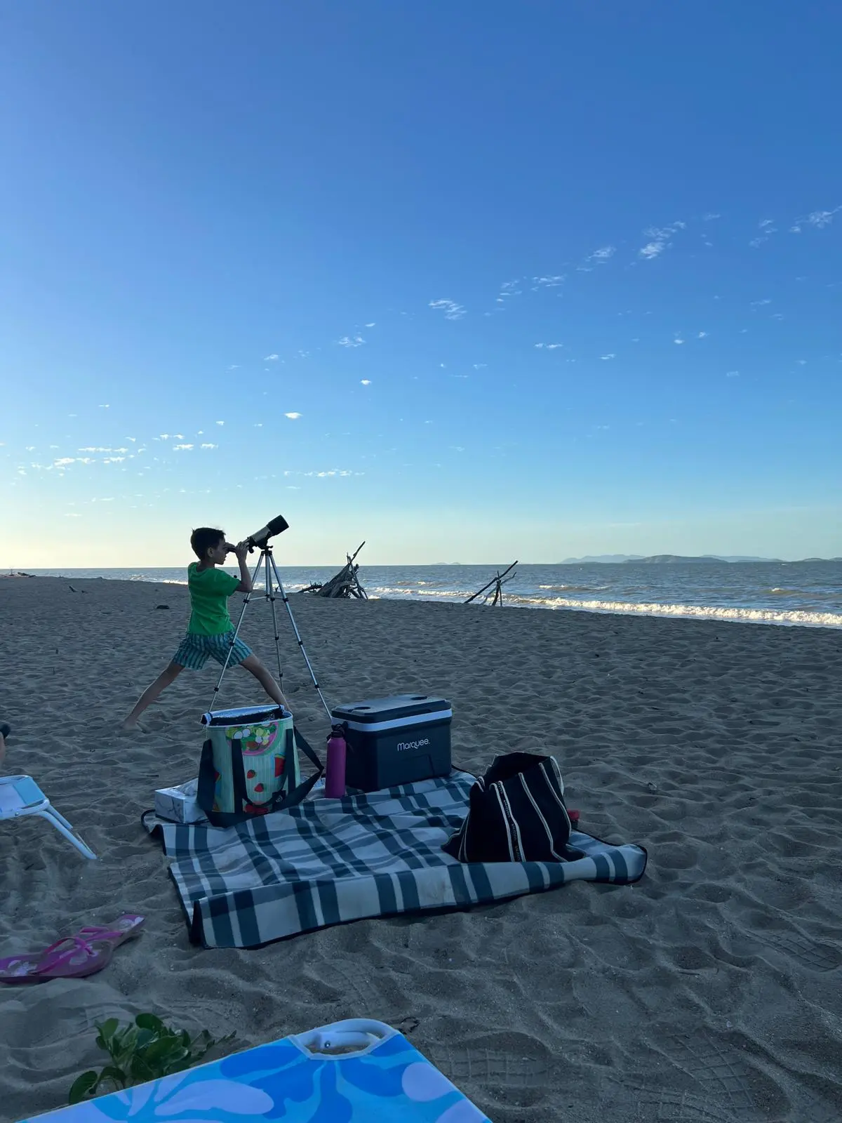 Young boy using a telescope on Saunders Beach for afternoon stargazing and wildlife spotting.