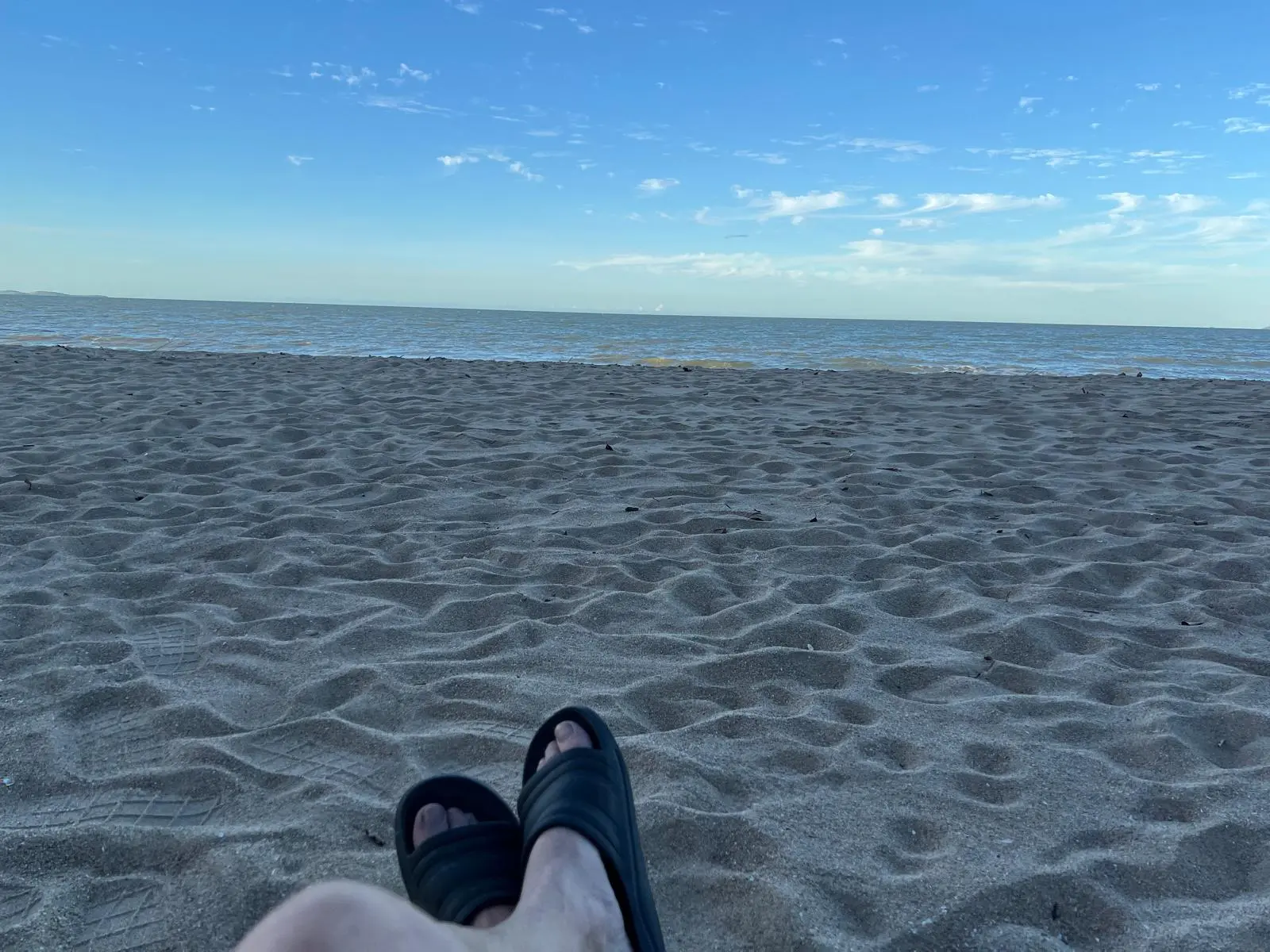 Relaxed POV of feet in the sand at Saunders Beach, emphasizing a quiet Sunday vibe.